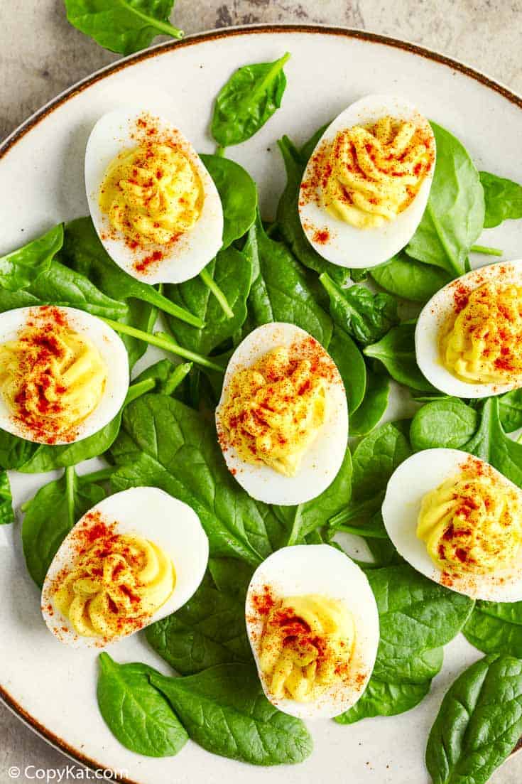 a plate of deviled eggs on top of fresh spinach leaves