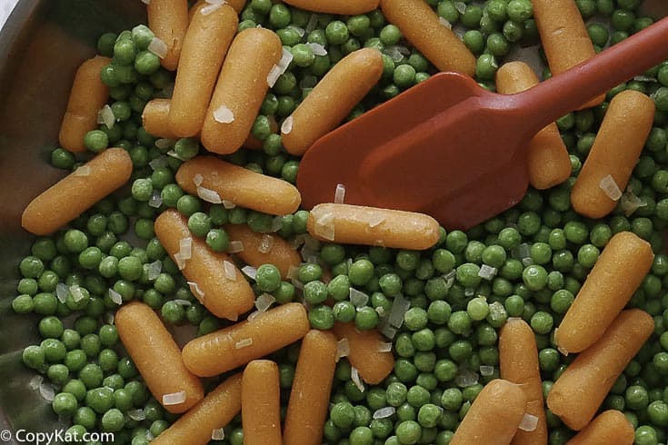 a skillet with peas and carrots
