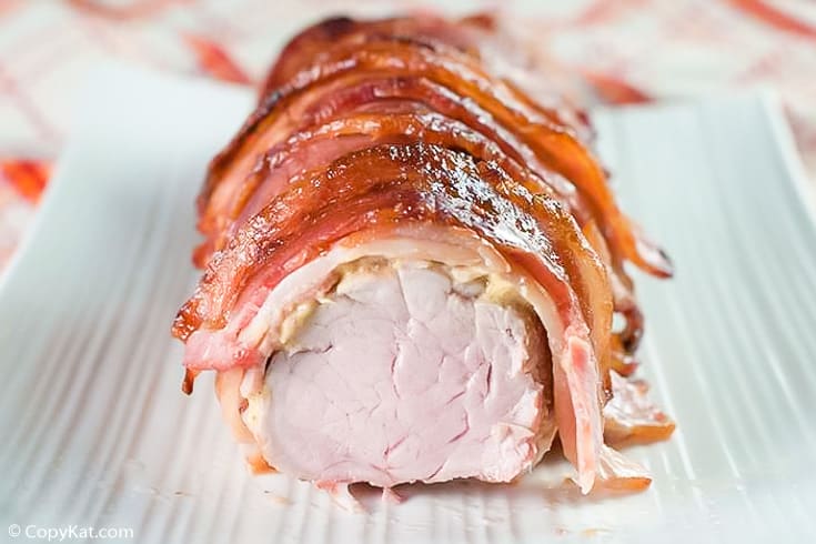 bacon wrapped pork tenderloin on a white platter