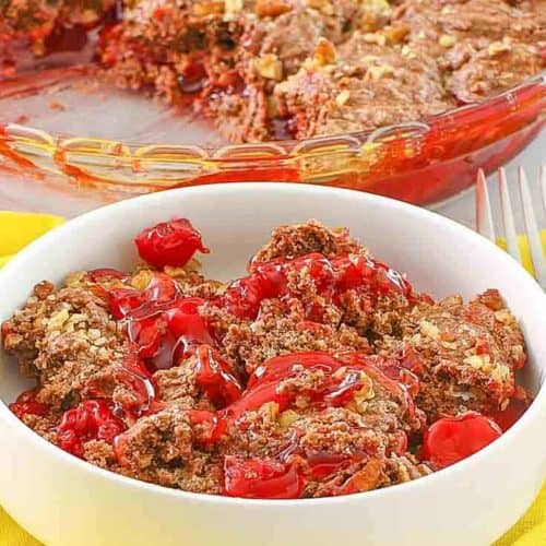 a bowl of cherry chocolate cobbler in front of the cobbler