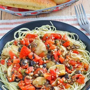 angel hair pasta with artichokes and a basket of breadsticks