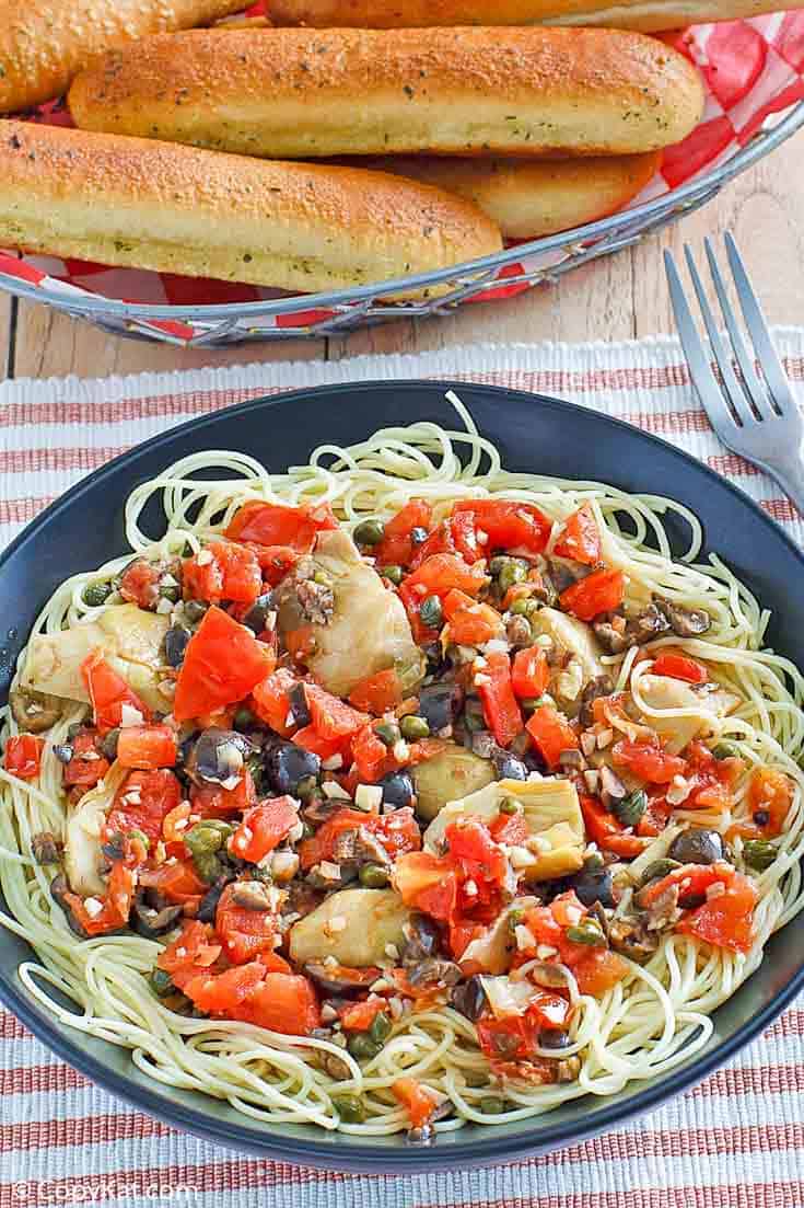 angel hair pasta with artichokes and a basket of breadsticks