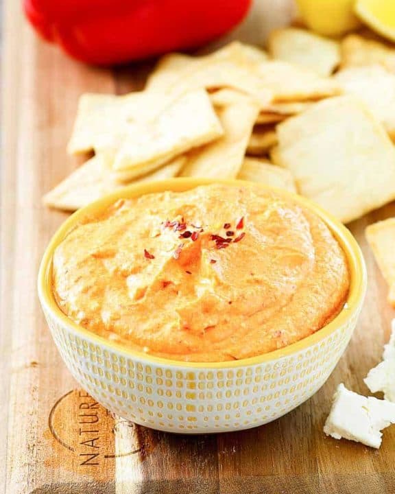 roasted red pepper dip in a bowl next to crackers