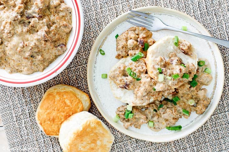 sausage gravy in a bowl and on top of biscuits