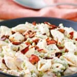 a bowl of pasta salad with bacon, carrots, peas, and ranch dressing