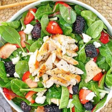 a bowl of salad with chicken, berries, and feta cheese