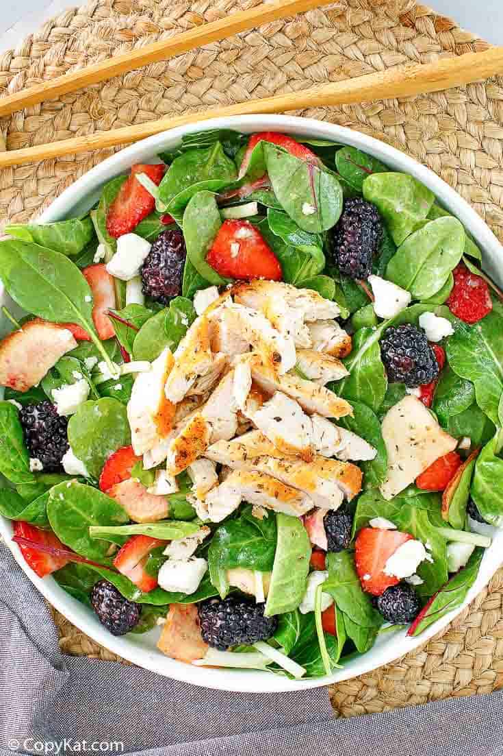 a bowl of salad with chicken, berries, and feta cheese