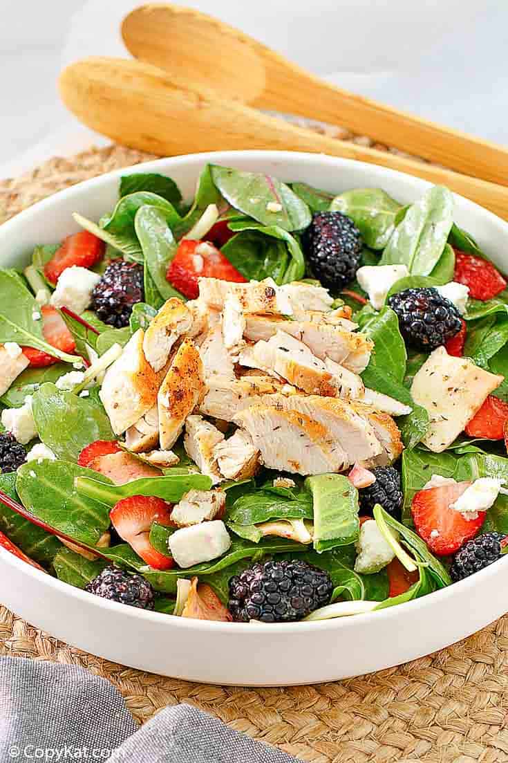a salad with grilled chicken, berries, apples, and feta cheese