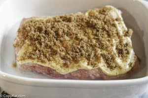corned beef topped with mustard and brown sugar in a baking dish.