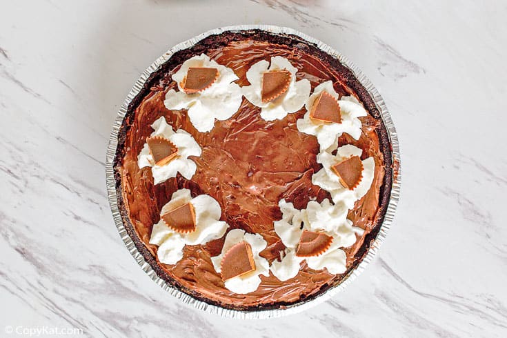 a whole chocolate peanut butter ice cream pie topped with whipped cream and Reeses peanut butter cups