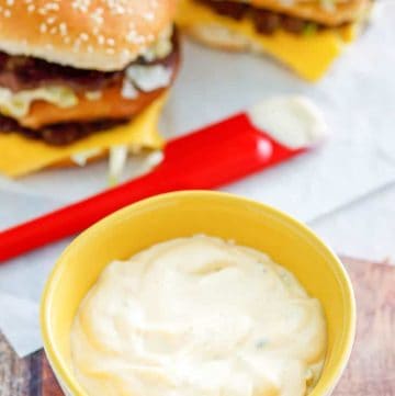 homemade Big Mac special sauce in a small bowl and two homemade Big Mac burgers
