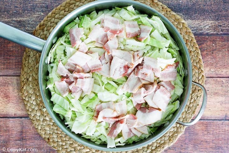 chopped green cabbage and bacon in a pan