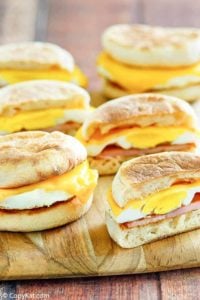 four homemade egg mcmuffins on a wood platter