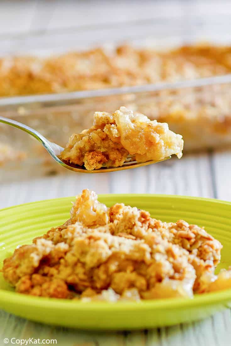 apple crisp on a fork over a plate with apple crisp