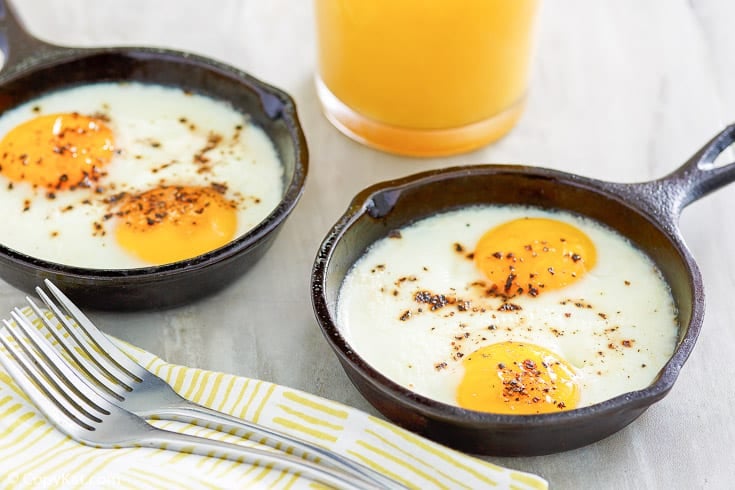 two cast iron skillets with baked eggs