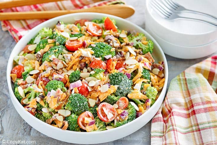 broccoli salad in a serving bowl with small bowls and forks beside it