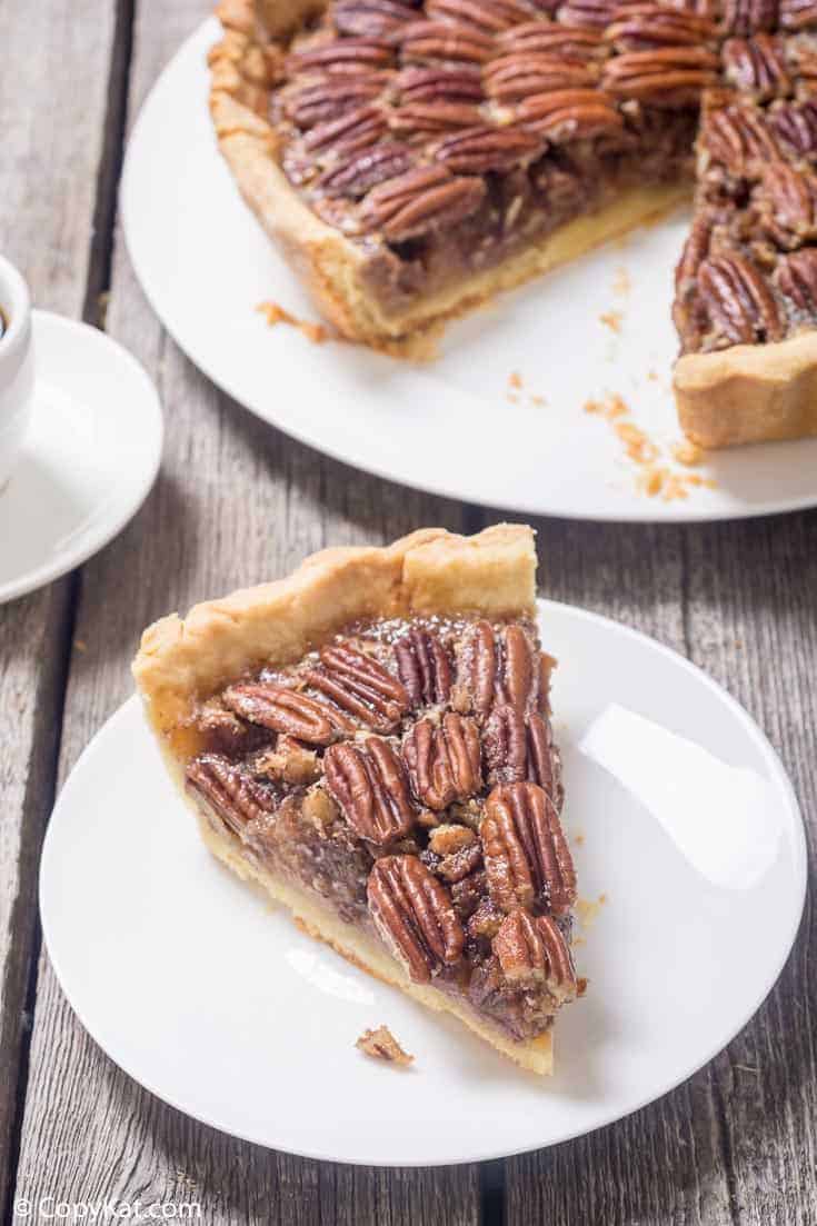 a slice of pecan pie on a white plate next to the pie