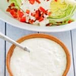 a bowl of blue cheese dressing next to a wedge salad