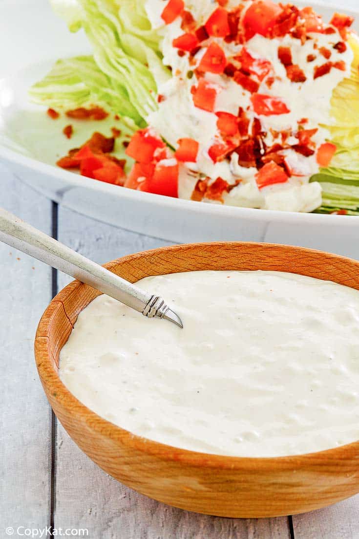 a bowl of homemade Chart House blue cheese dressing in front of a wedge salad