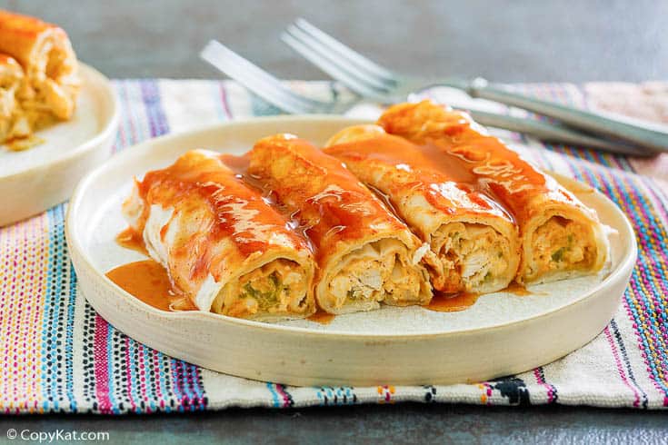 four cream cheese chicken enchiladas topped with sauce on a plate