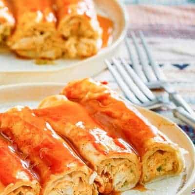 cuatro enchiladas de pollo con queso crema y salsa en un plato
