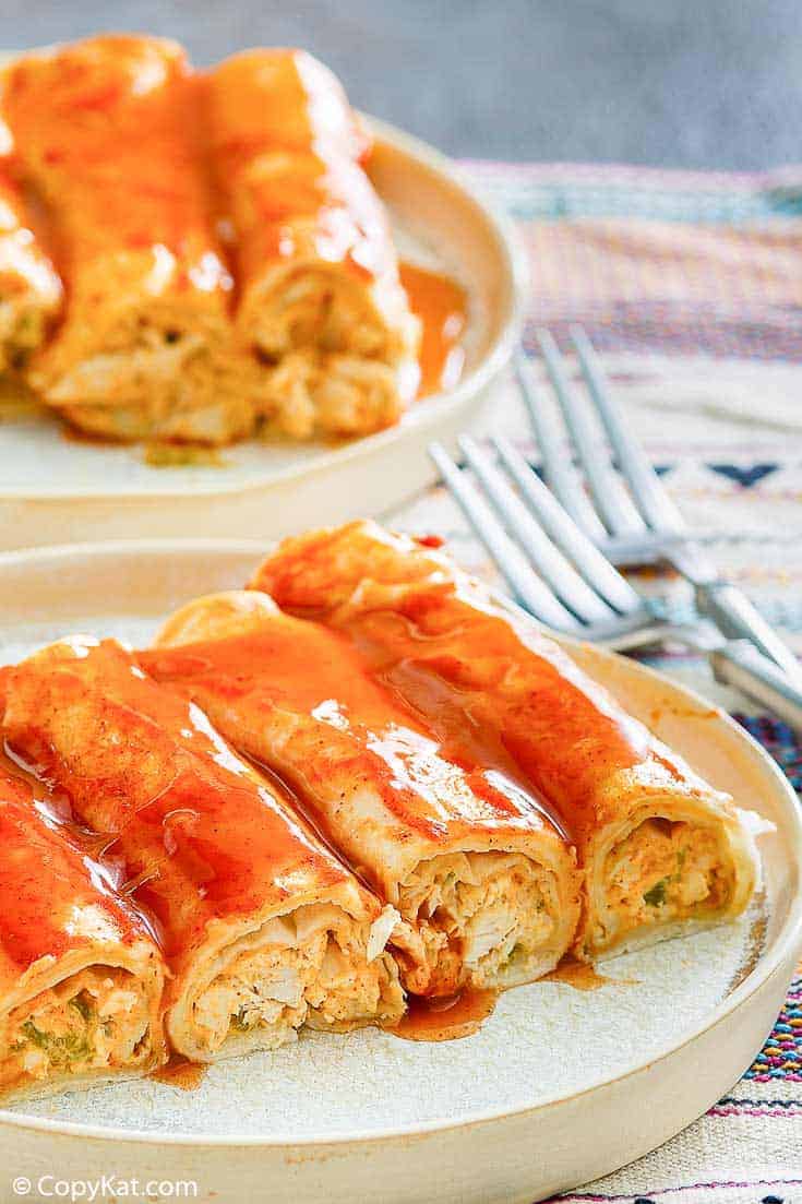 four cream cheese chicken enchiladas and sauce on a plate