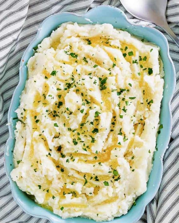 old fashioned mashed potatoes in a blue dish next to a serving spoon