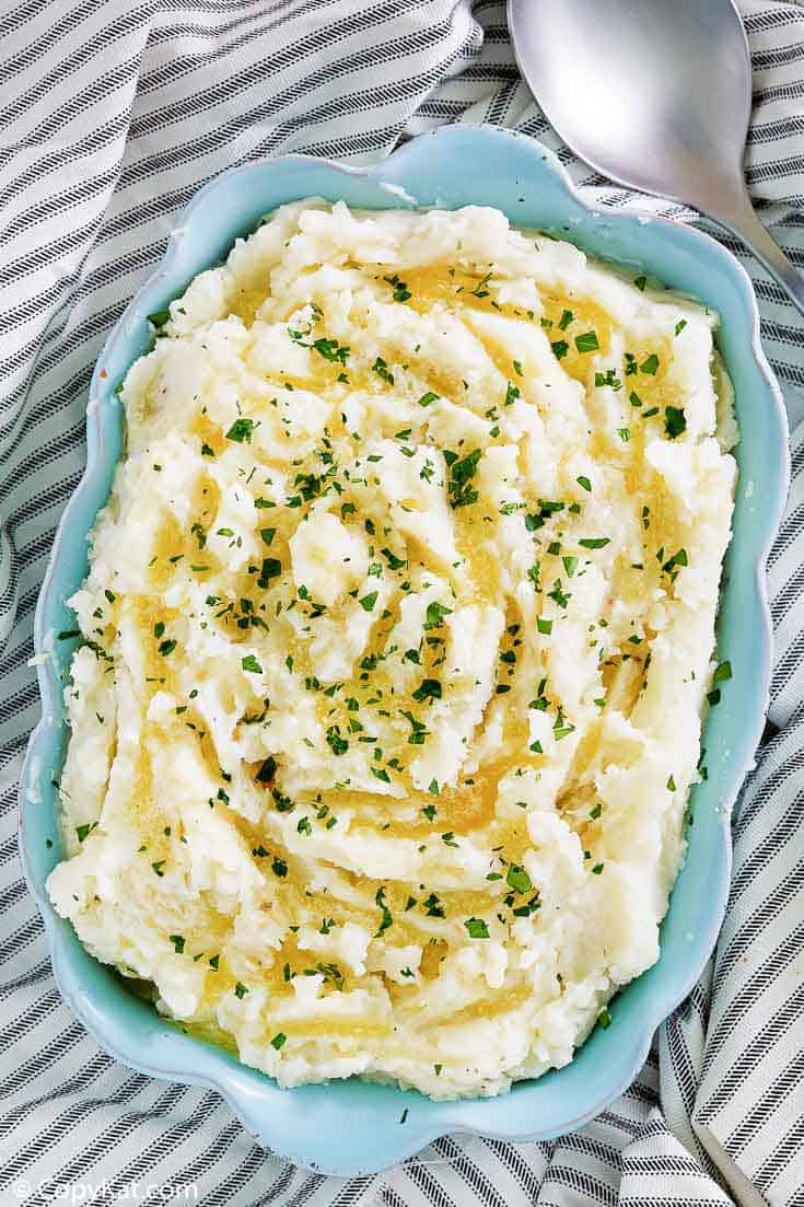 old fashioned mashed potatoes in a blue dish next to a serving spoon