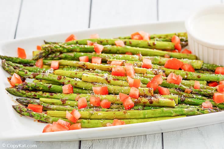 parmesan roasted asparagus, balsamic drizzle, chopped tomatoes, and cheese sauce on a platter