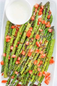 Homemade Olive Garden Parmesan Roasted Asparagus with balsamic drizzle and cheese sauce on a platter