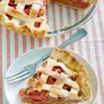 a slice of rhubarb custard pie on a white plate next to the pie