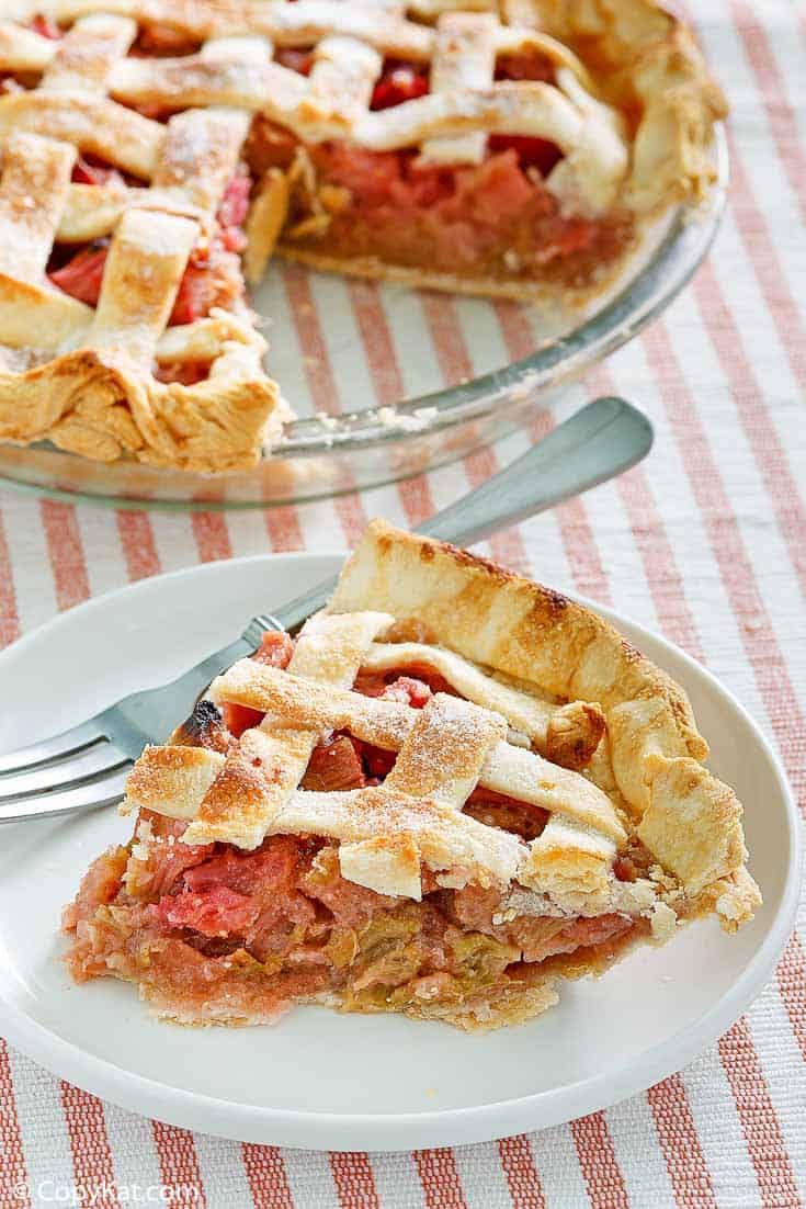 a slice of rhubarb custard pie on a plate next to the pie