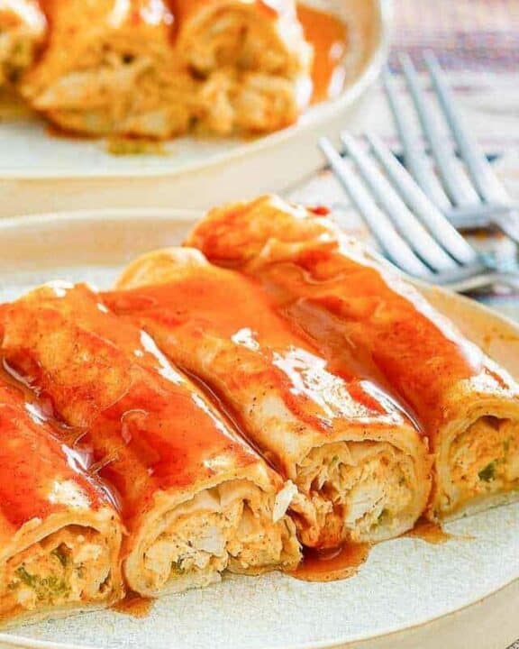 four cream cheese chicken enchiladas and sauce on a plate