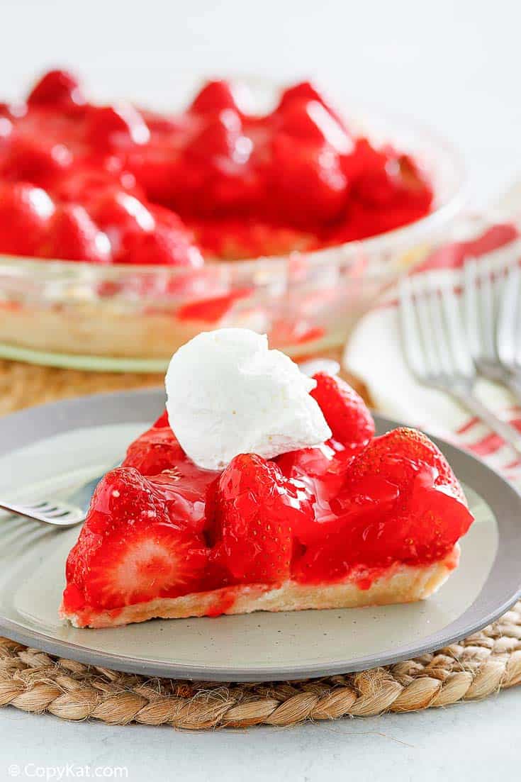 a slice of fresh strawberry pie with a dollop of whipped cream on top