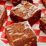 frosted chocolate brownies with nuts on parchment paper