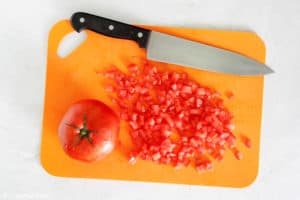 chopped tomatoes and a knife on a cutting board