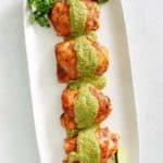 overhead view of Peruvian chicken thighs with green sauce on a platter