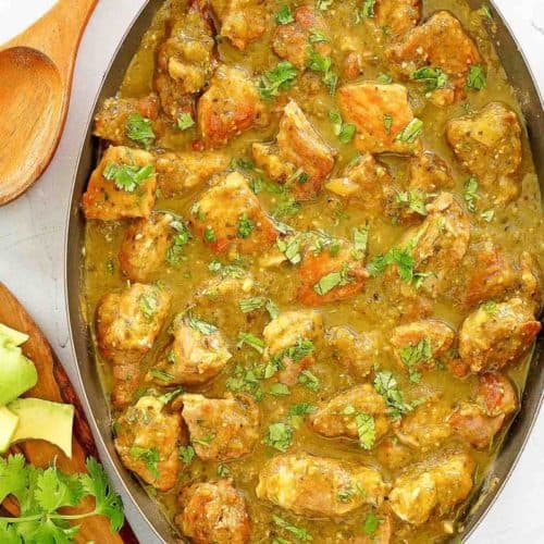 chili verde in a skillet and a wooden spoon