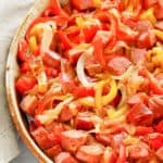 Smoked sausage, peppers, and onions in a brown serving dish