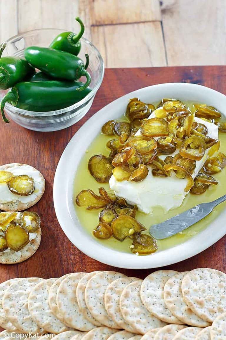 candied jalapenos over cream cheese on a platter next to crackers