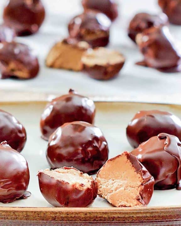 chocolate peanut butter balls on a plate and parchment paper