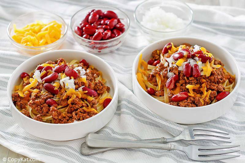 two bowls of Cincinnati chili and small bowls of cheese, kidney beans, and chopped onions