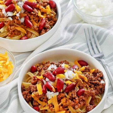 bowls of Cincinnati chili topped with cheese, onions, and kidney beans