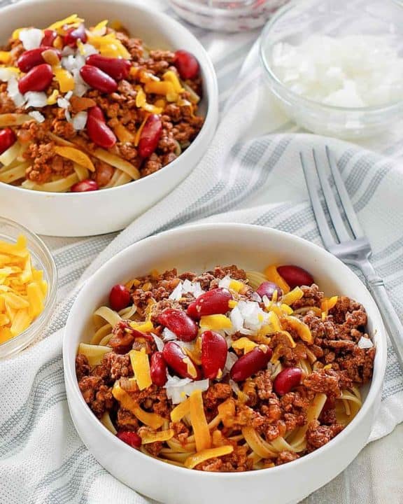 bowls of Cincinnati chili topped with cheese, onions, and kidney beans