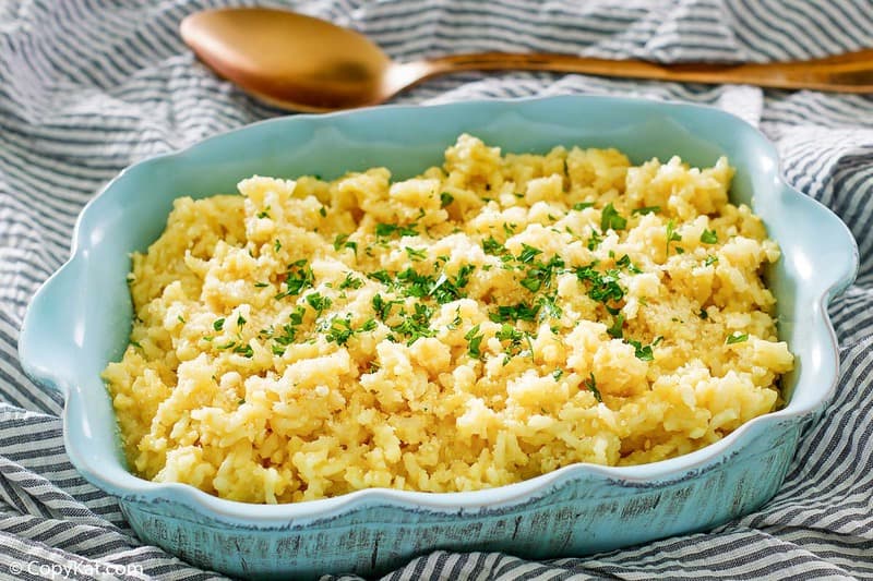 Parmesan risotto in a blue serving dish and a serving spoon