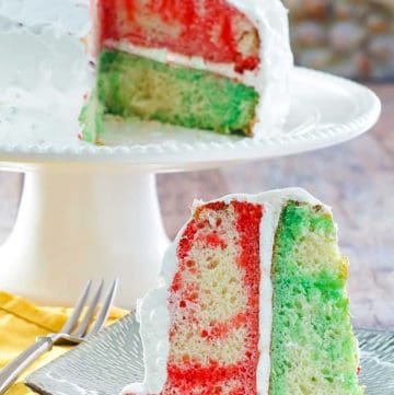 a slice of Jello poke cake in front the the cake on a stand