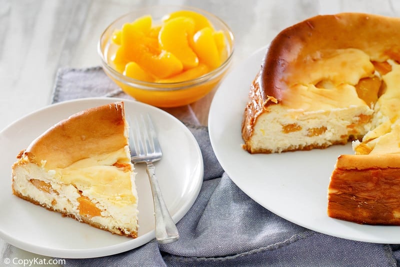 a slice of peaches and cream cheesecake, a bowl of peach slices, and a peach cheesecake