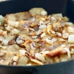 pan fried sliced potatoes and onions in a skillet