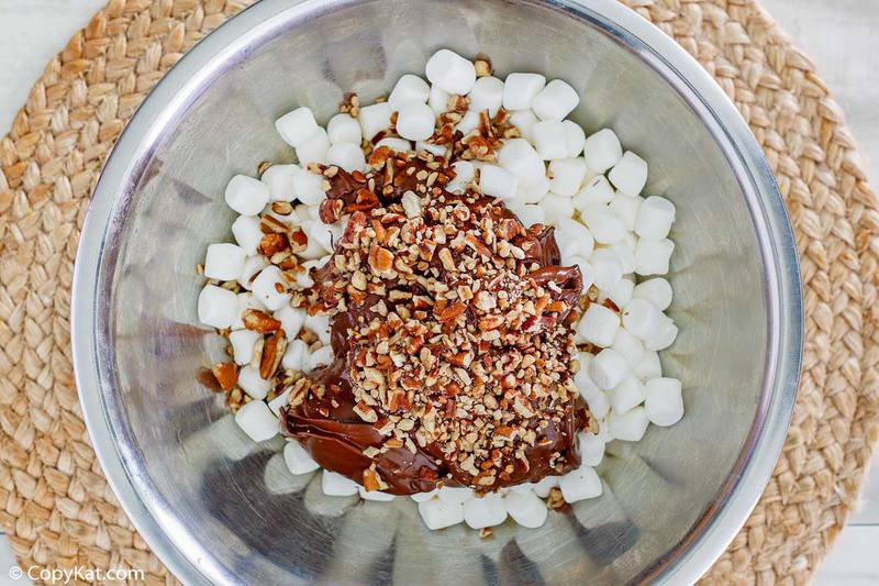 melted chocolate, miniature marshmallows, and chopped pecans in a mixing bowl
