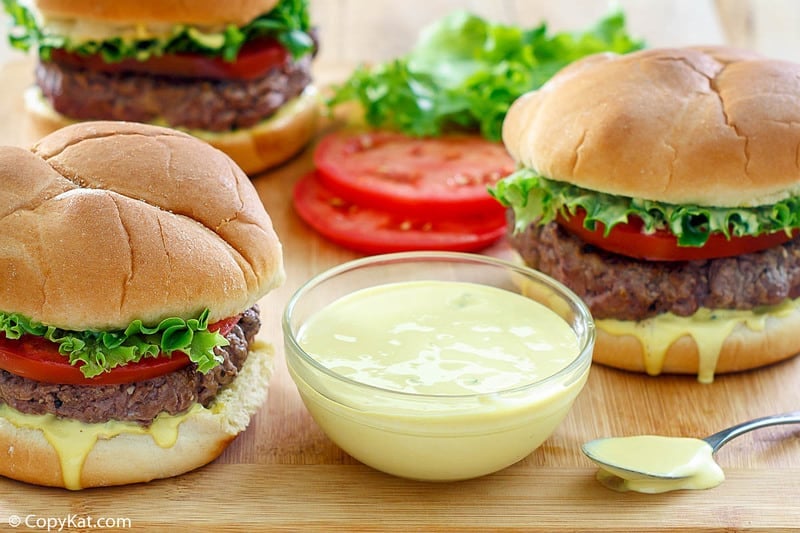 a bowl of homemade Smashburger Smash Sauce and three burgers